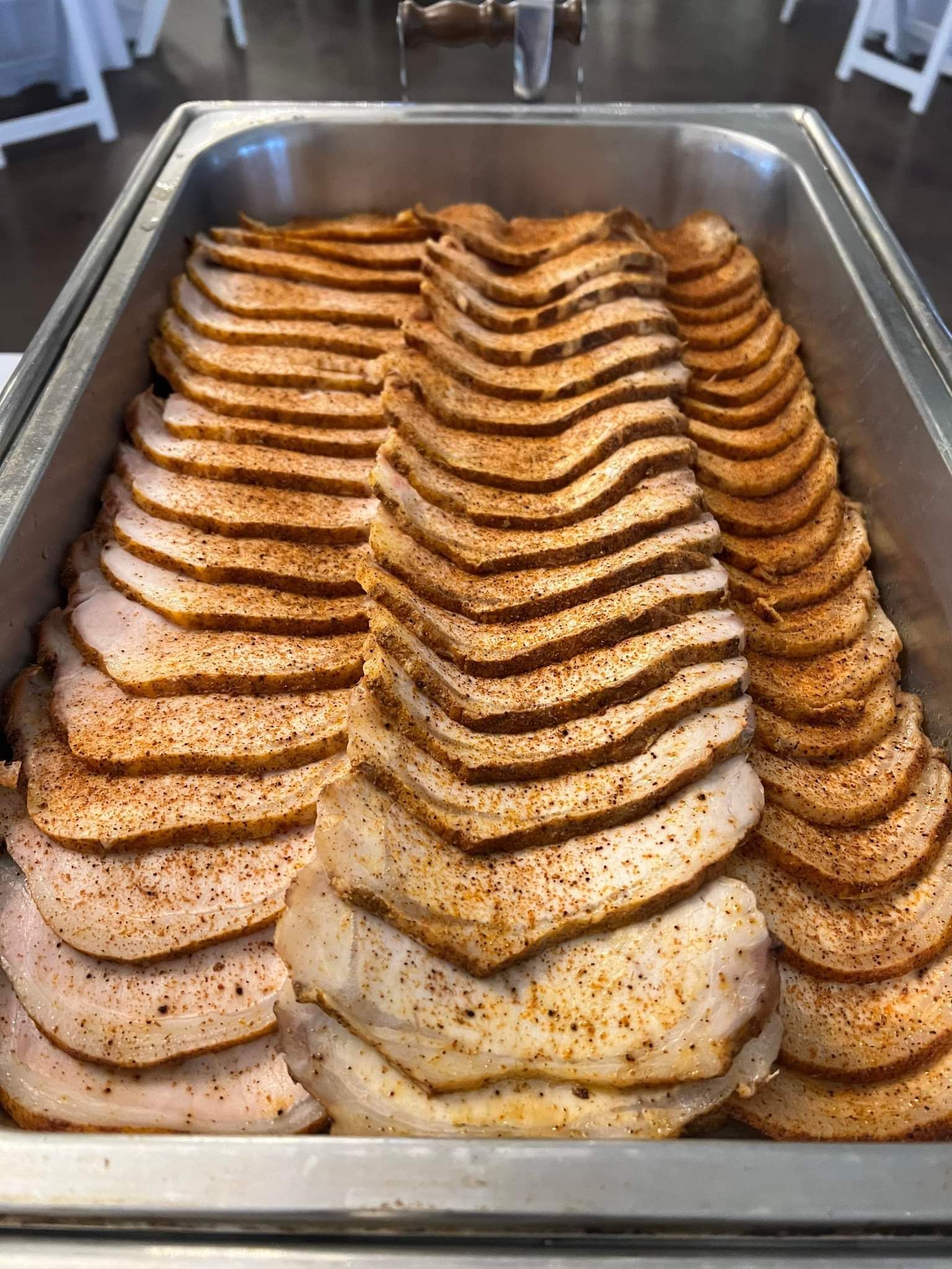 A metal tray filled with sliced turkey breast.