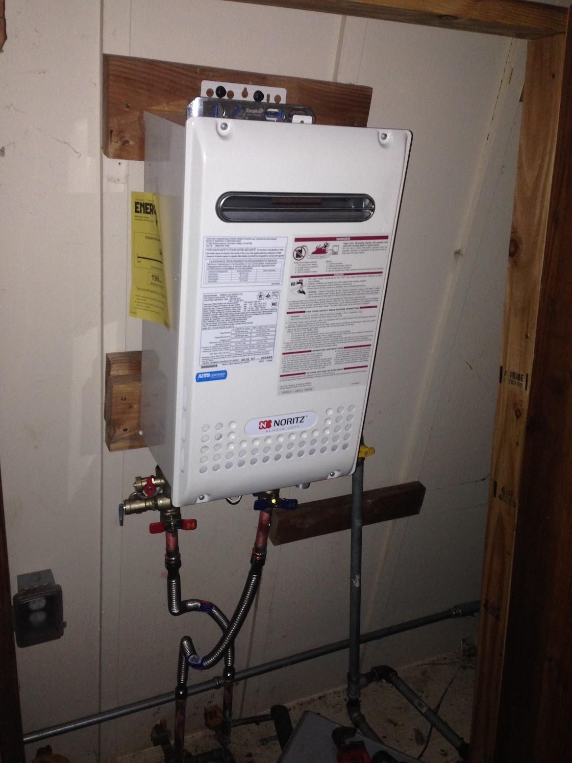 Tankless water heater mounted on a wall, with pipes and controls.