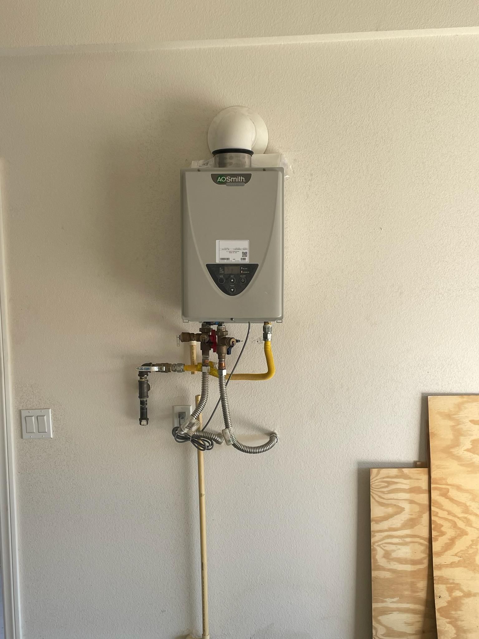 Gas water heater mounted on a textured wall with visible pipes and venting.