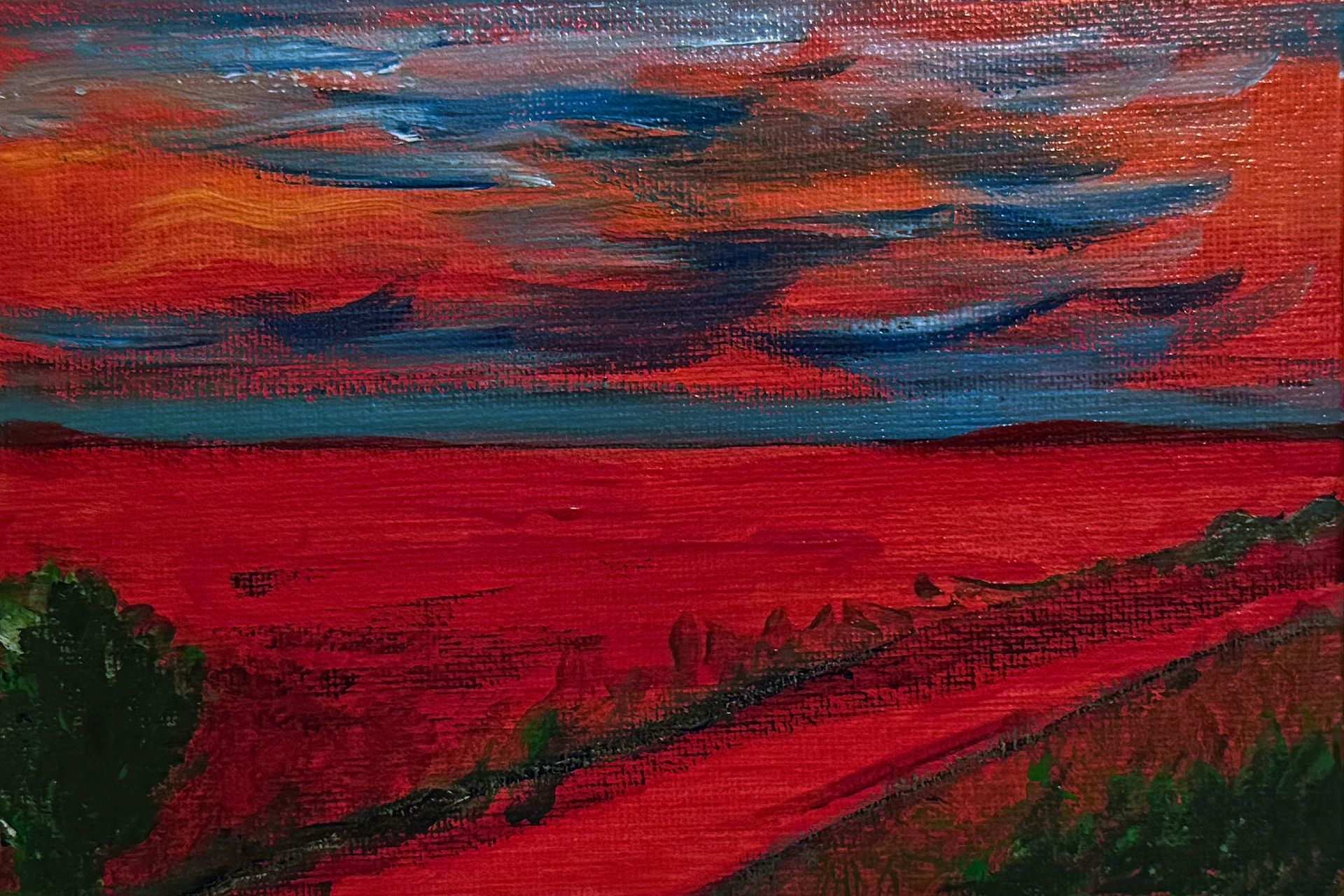 Abstract rood en blauw landschap met een dramatische bewolkte hemel aan de horizon en donkere bomen op de voorgrond.