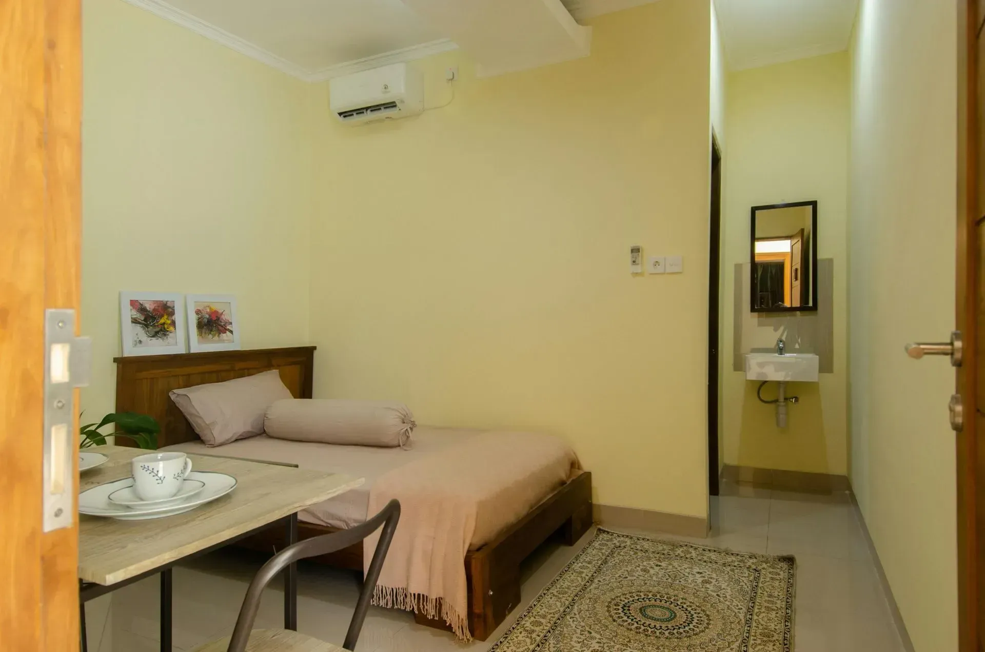 A bedroom with a bed , table , chair and sink.