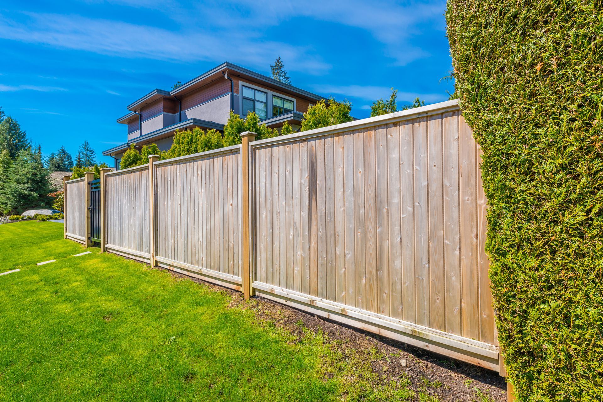 A wooden fence surrounds a lush green yard