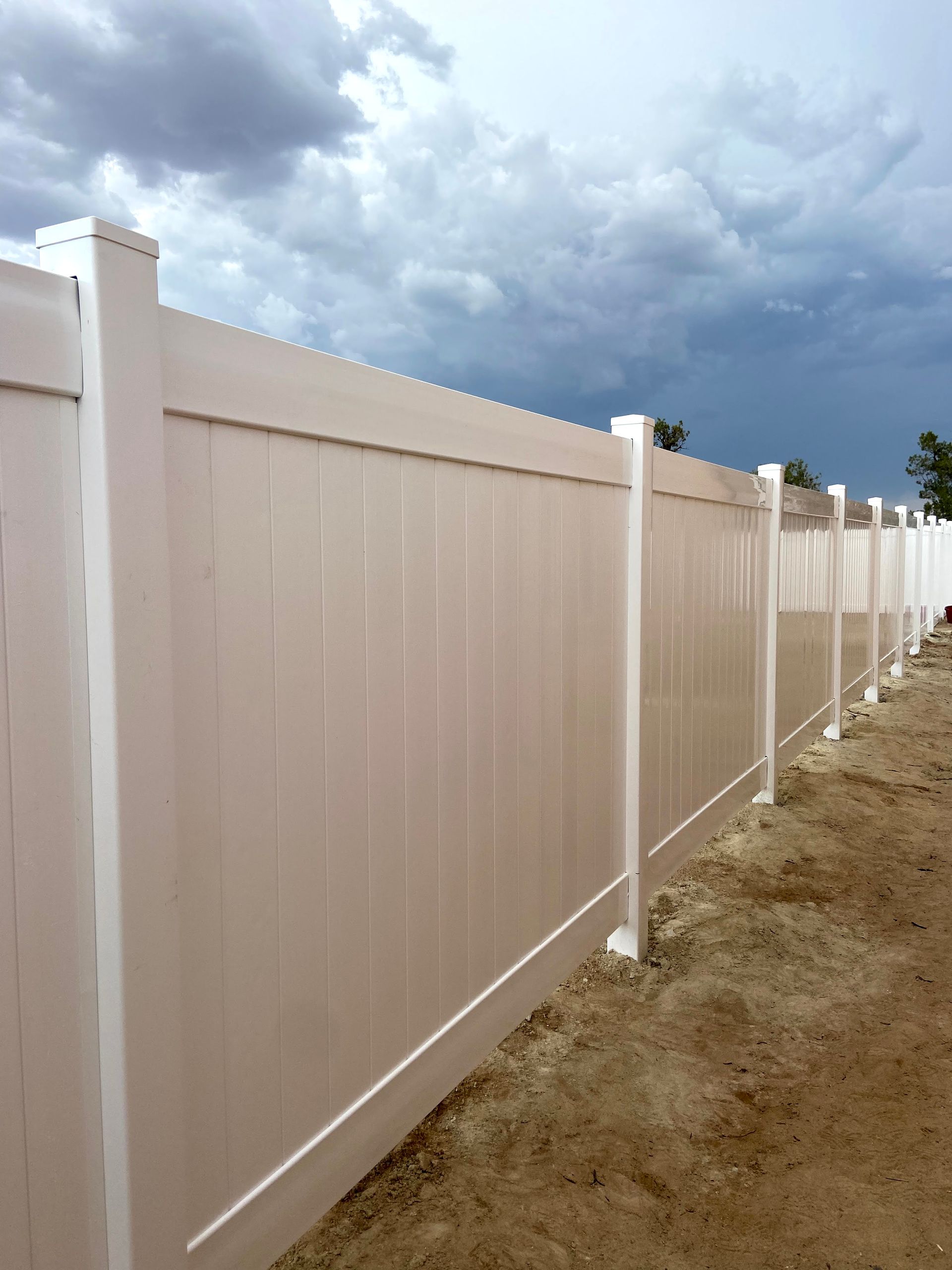 A white fence with a cloudy sky in the background