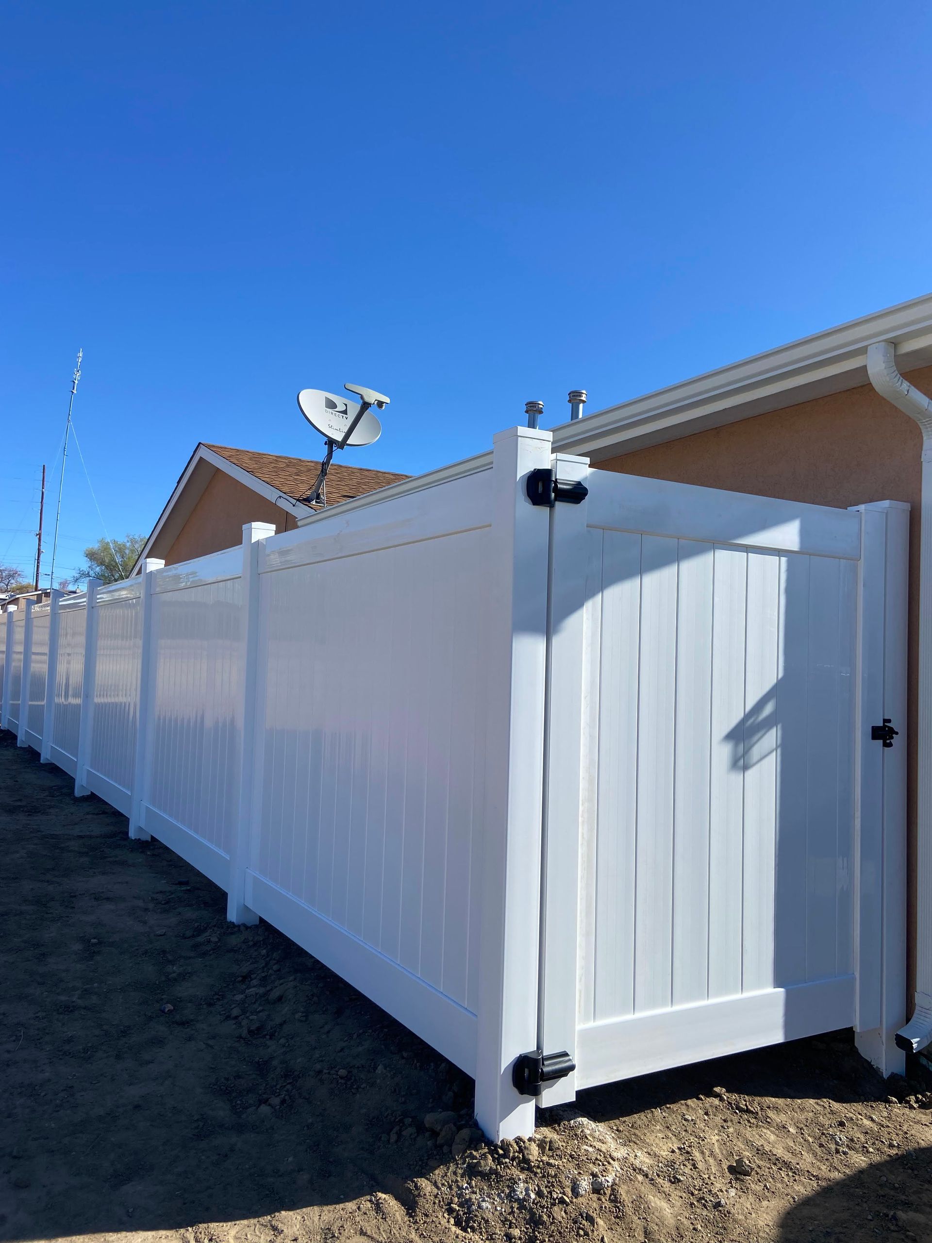 A white fence with a gate in front of a house.