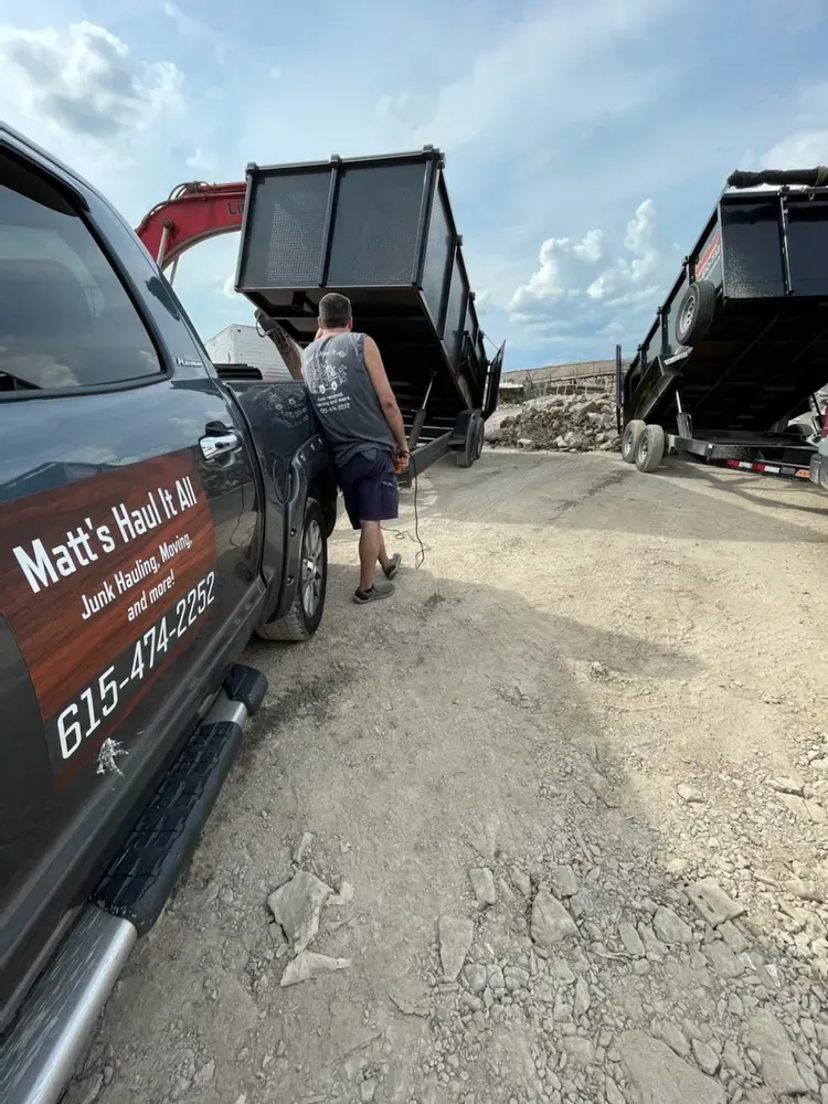 A man is loading a dumpster into a truck.