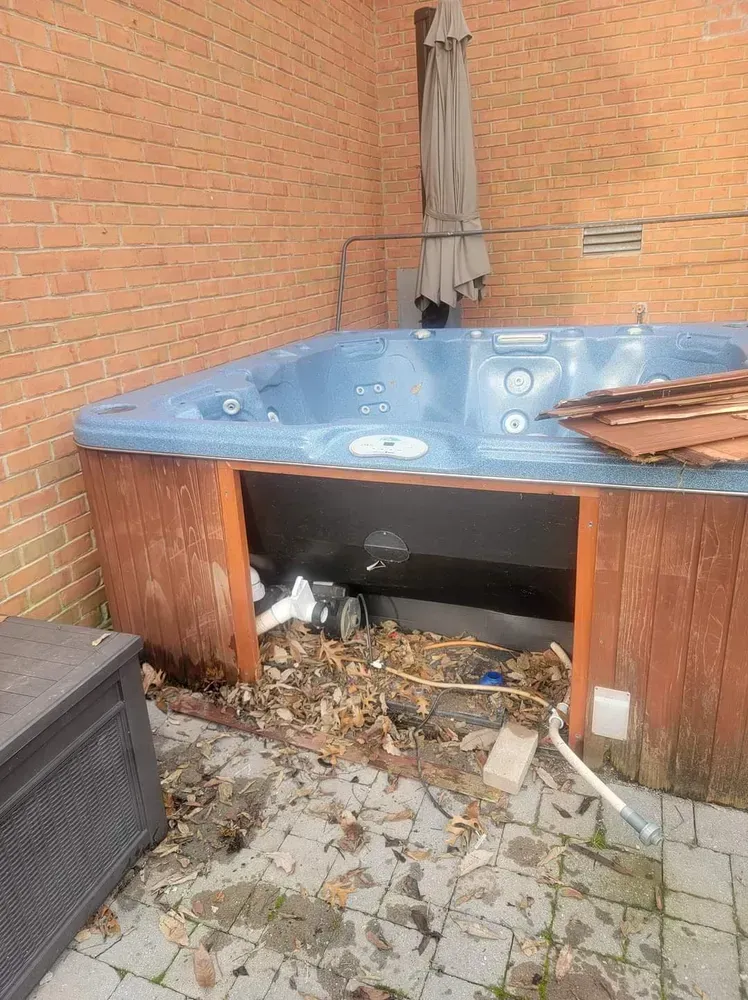 A hot tub is sitting on a brick patio next to a brick wall.