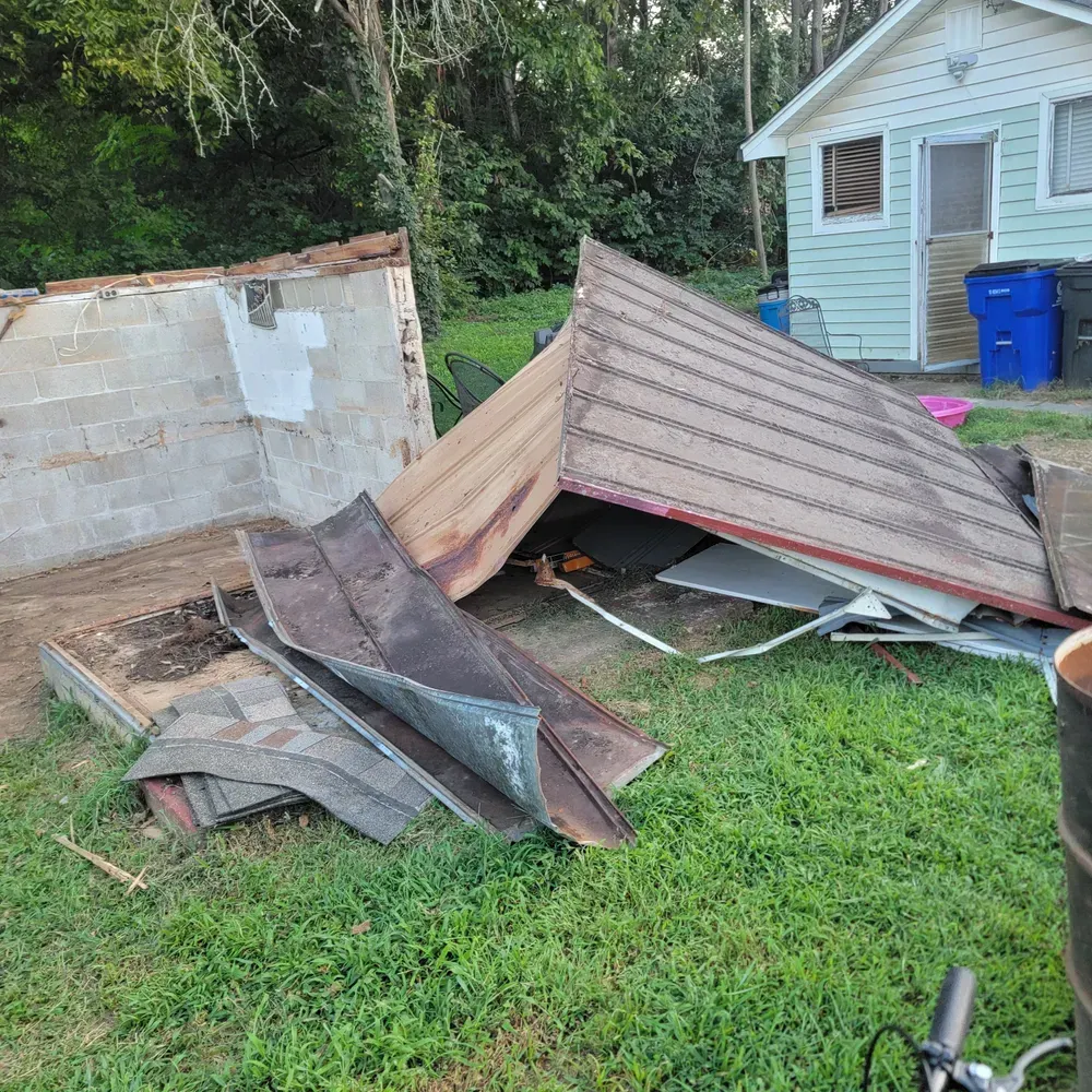 A roof is laying on the ground in front of a house.