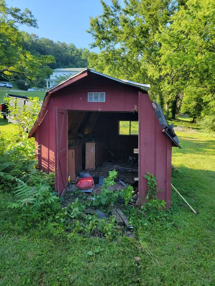 A red barn is sitting in the middle of a grassy field.