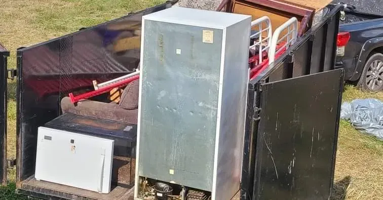 A refrigerator is sitting in the back of a dumpster.