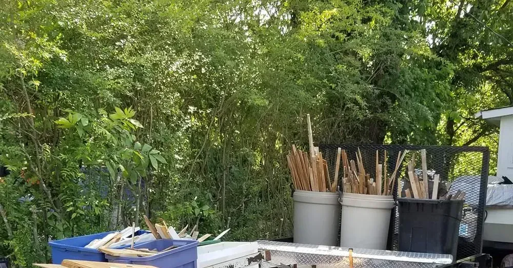 A dumpster with a lot of trash on it is parked in the woods.