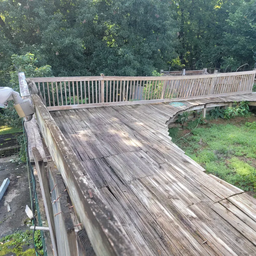 A wooden deck with a railing and trees in the background.