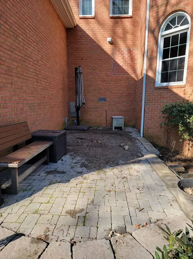 There is a bench and umbrella in the backyard of a brick building.