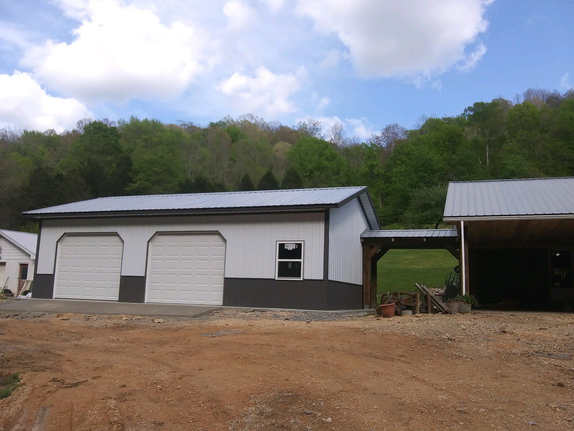 A white and black garage with a carport next to it