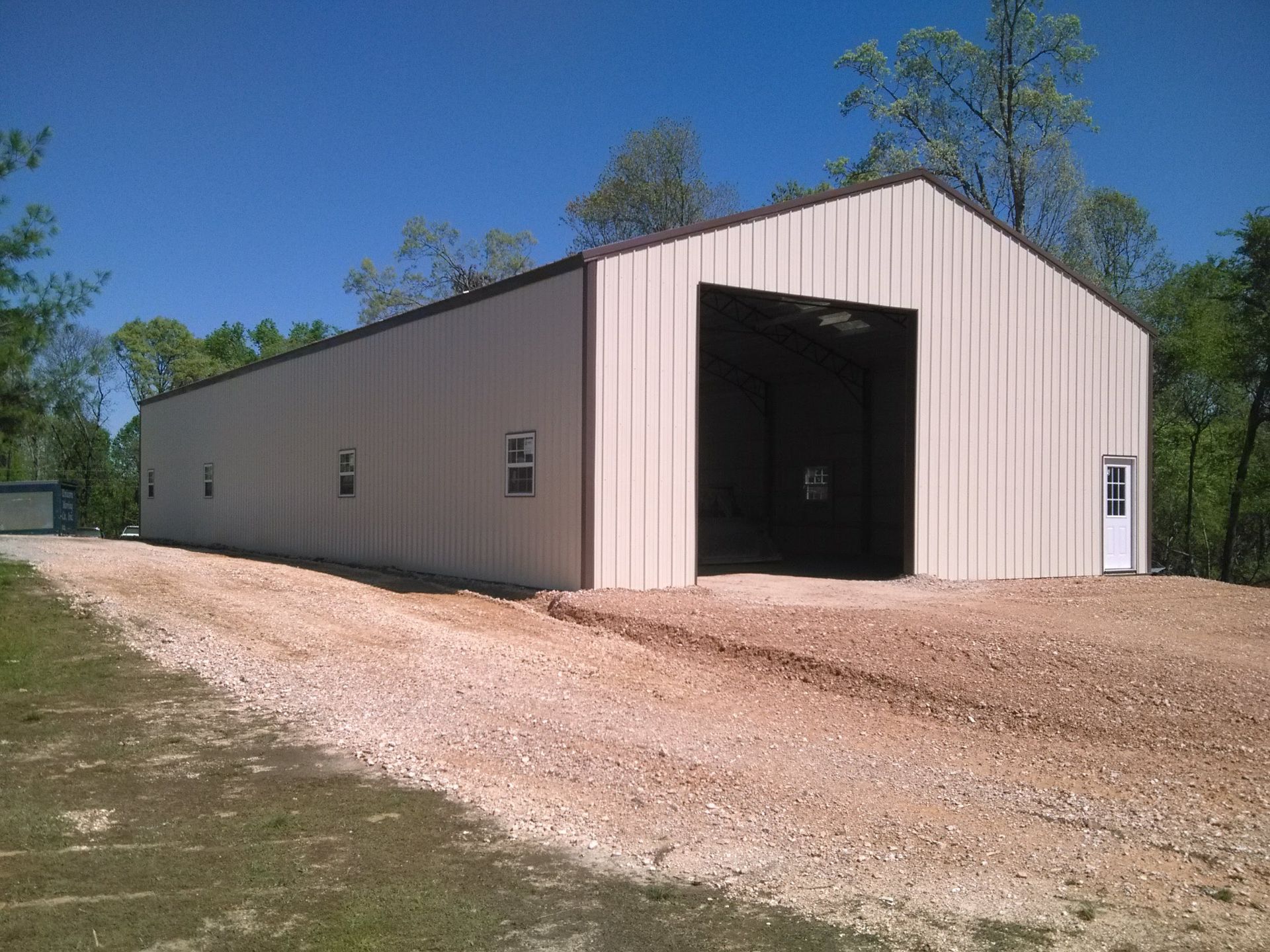 A large metal building is sitting on top of a gravel road.