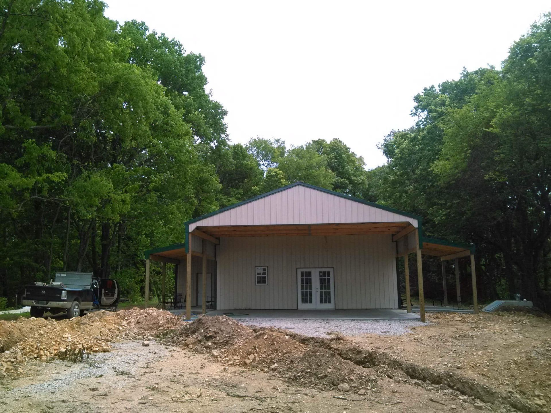 A large building with a porch is surrounded by trees