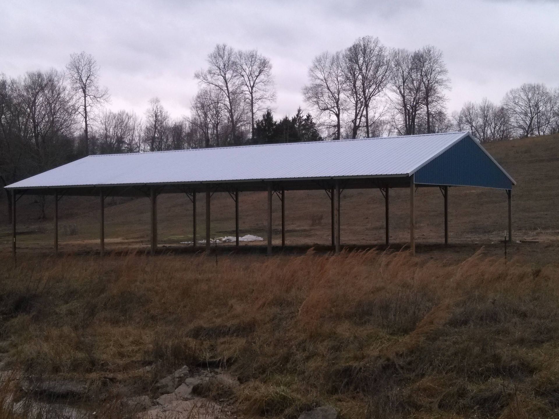A blue and white building in a field with trees in the background