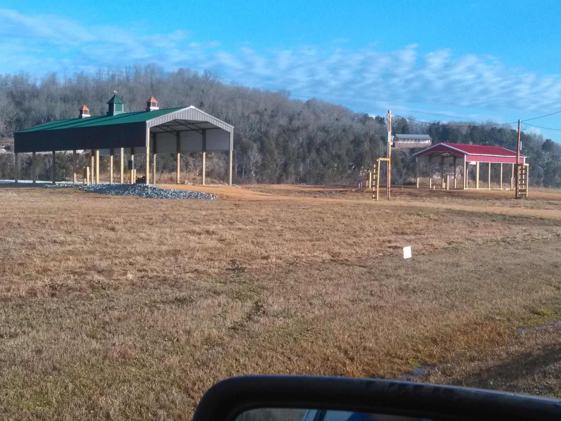 A rear view mirror shows a field with a building in the background