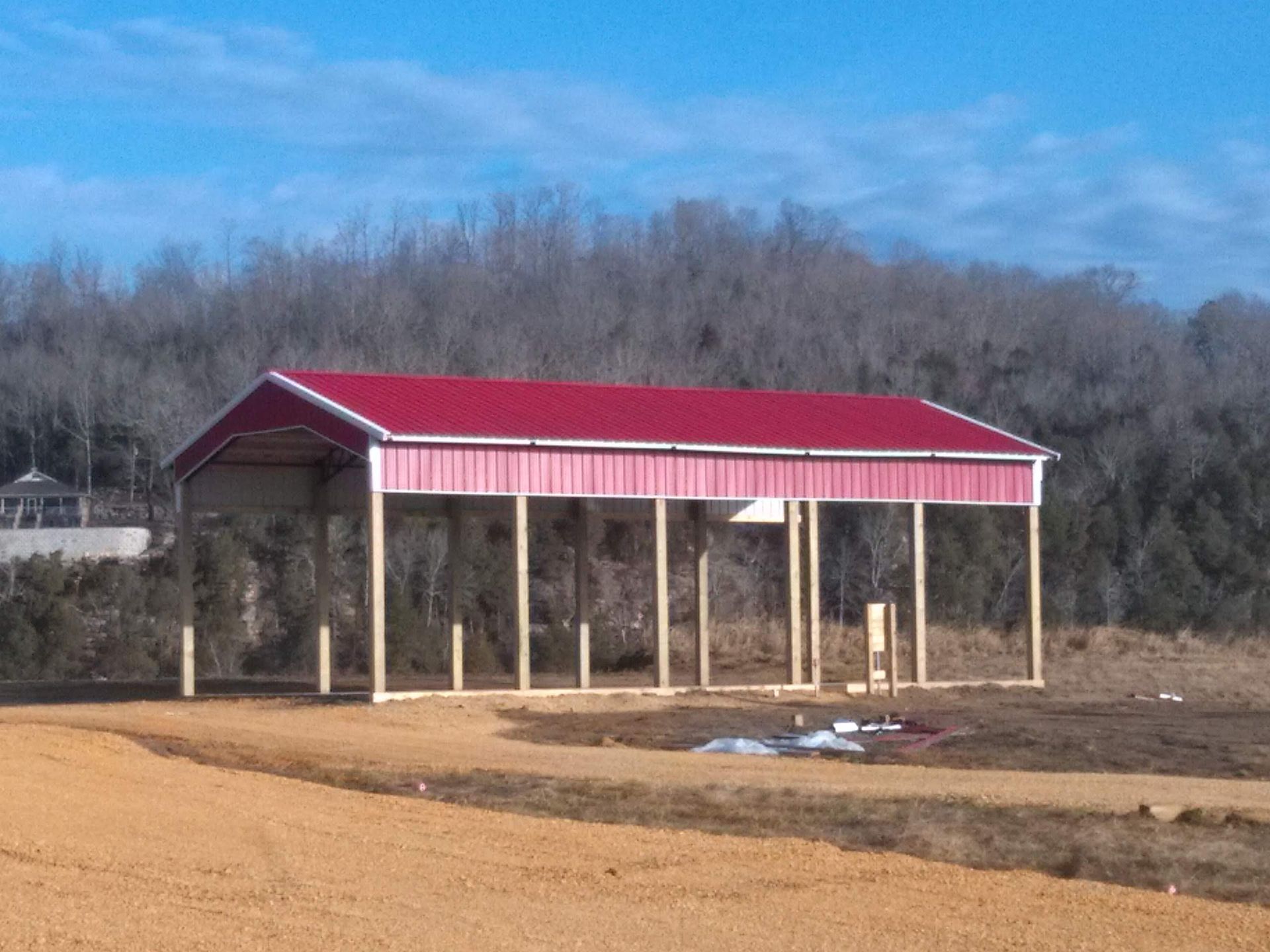 A red and white building is sitting in the middle of a dirt field.