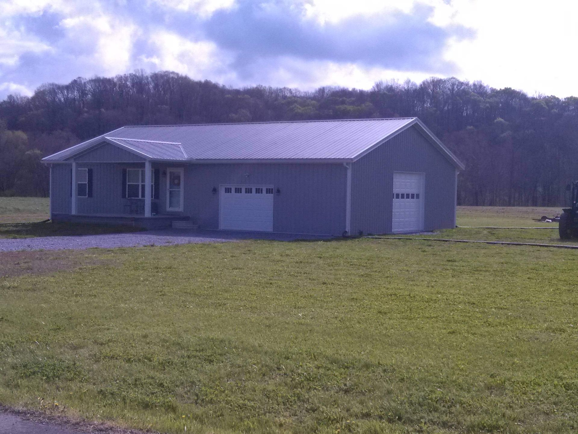 A house with a garage in the middle of a grassy field.