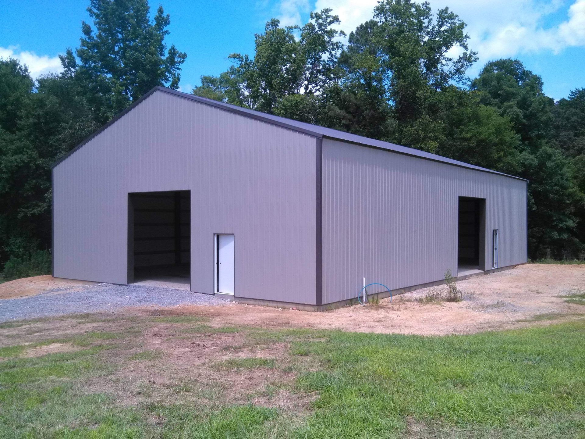 A large gray metal building is sitting in the middle of a grassy field