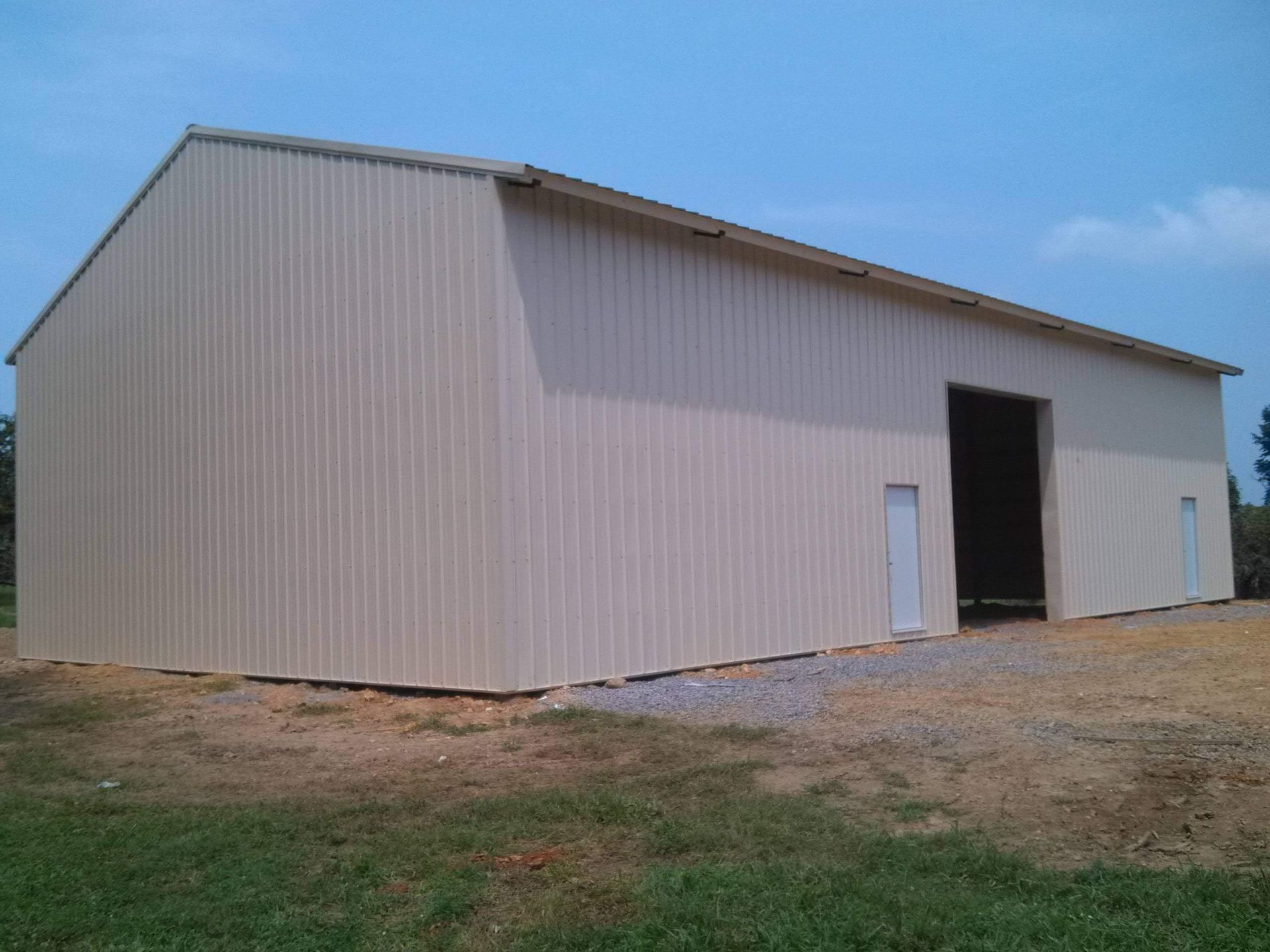 A large white building is sitting in the middle of a grassy field.