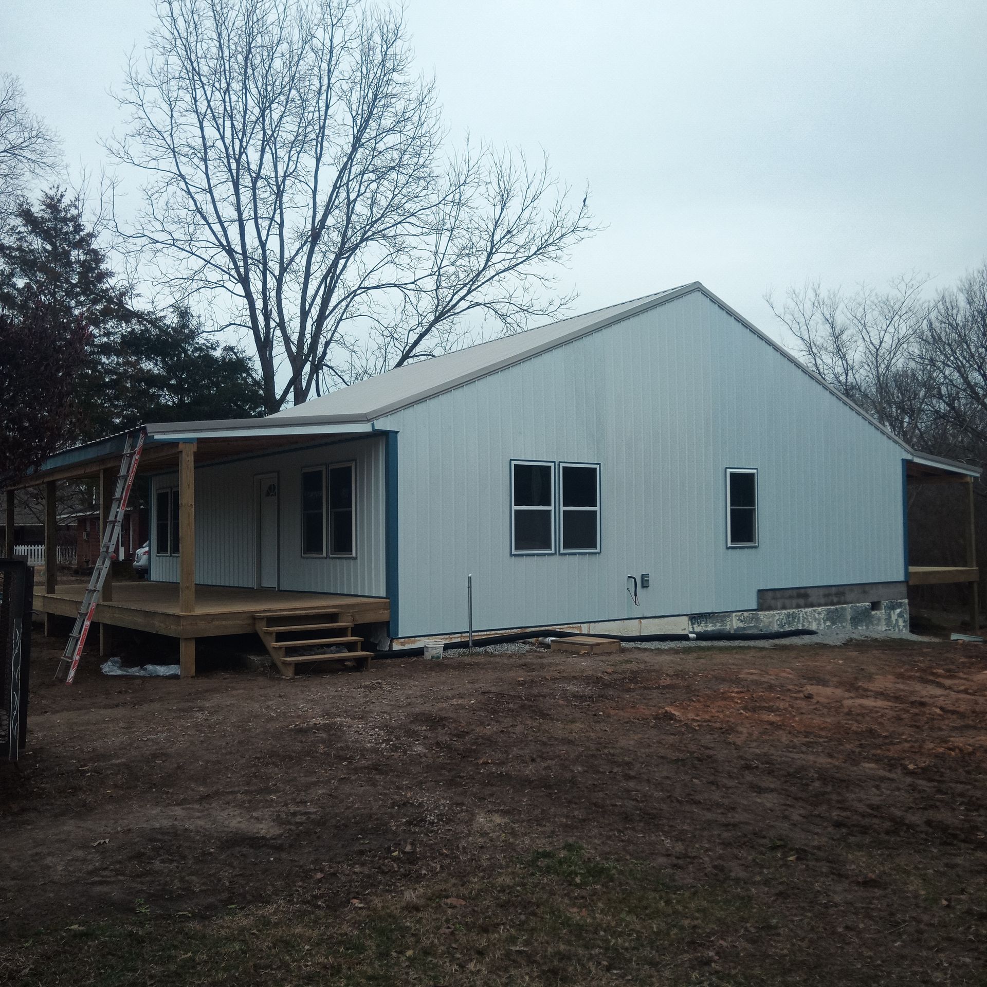 A white house with a porch and a ladder in front of it