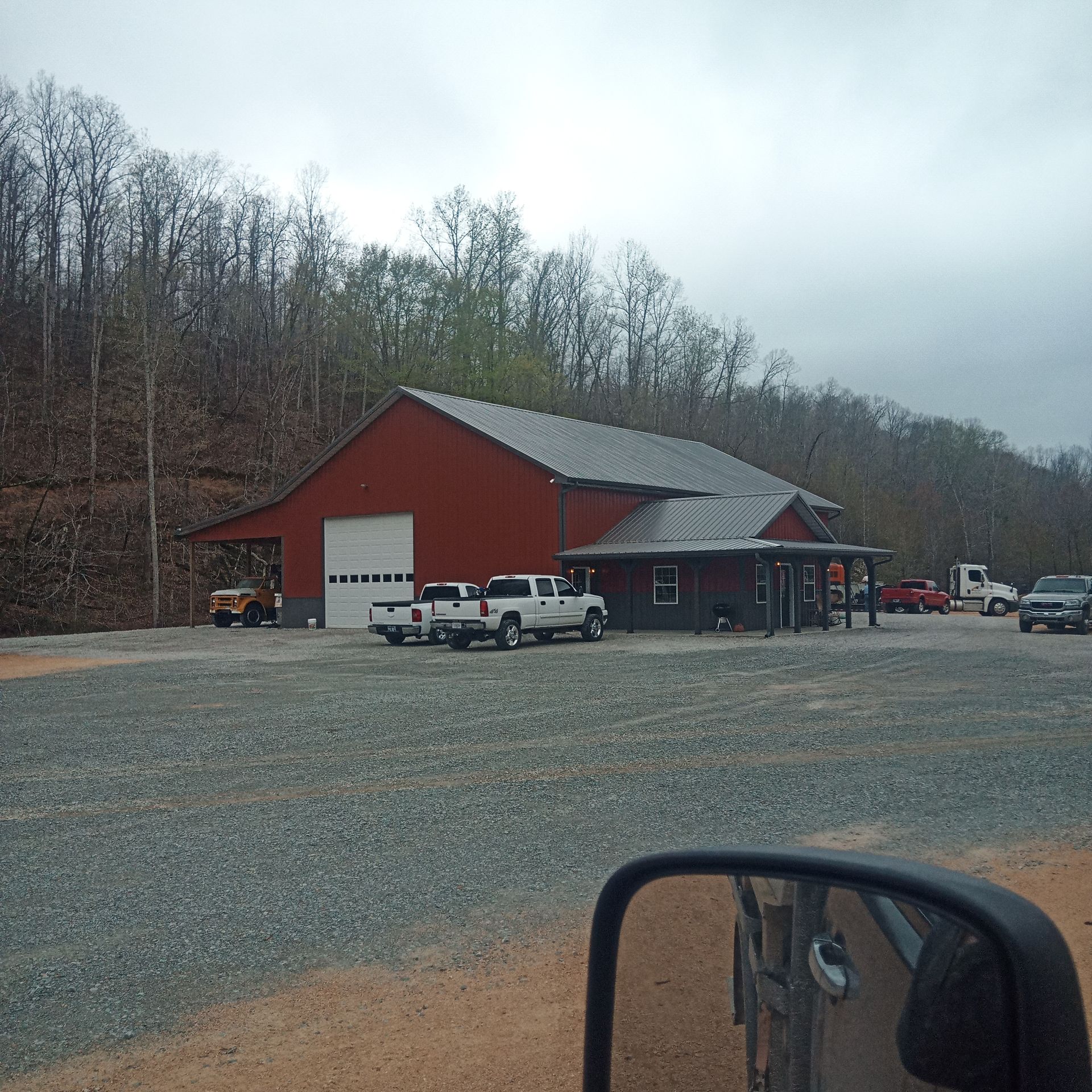 A white truck is parked in front of a red barn