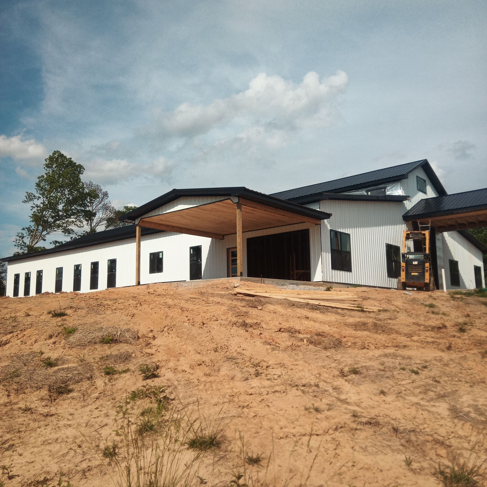A large white house is sitting on top of a dirt hill