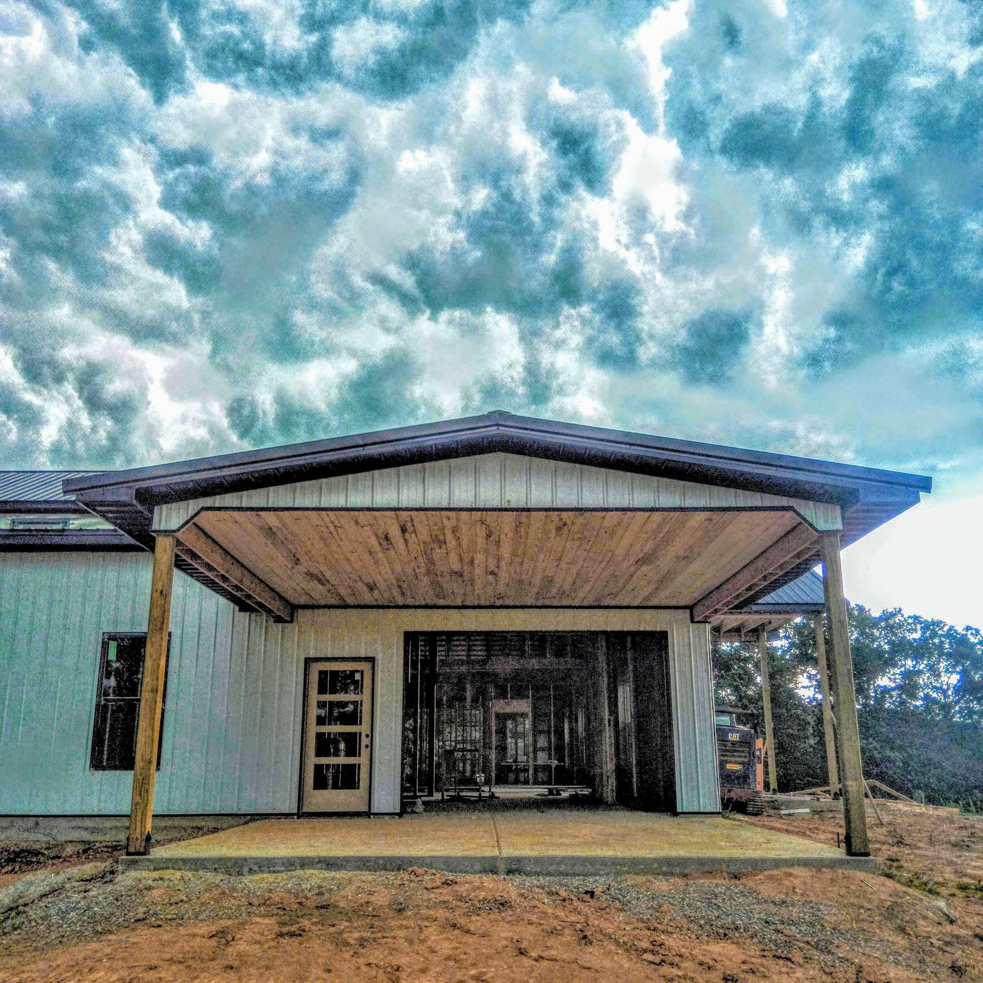 A white house with a wooden porch and a cloudy sky in the background.