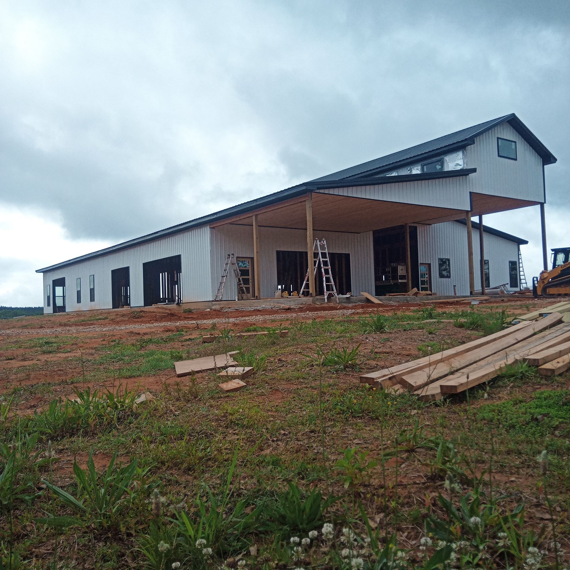 A large white building is being built on top of a dirt hill.