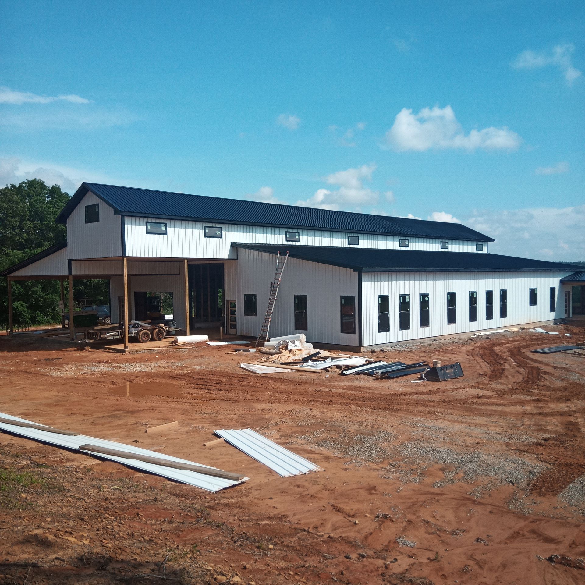 A large white building with a black roof is under construction