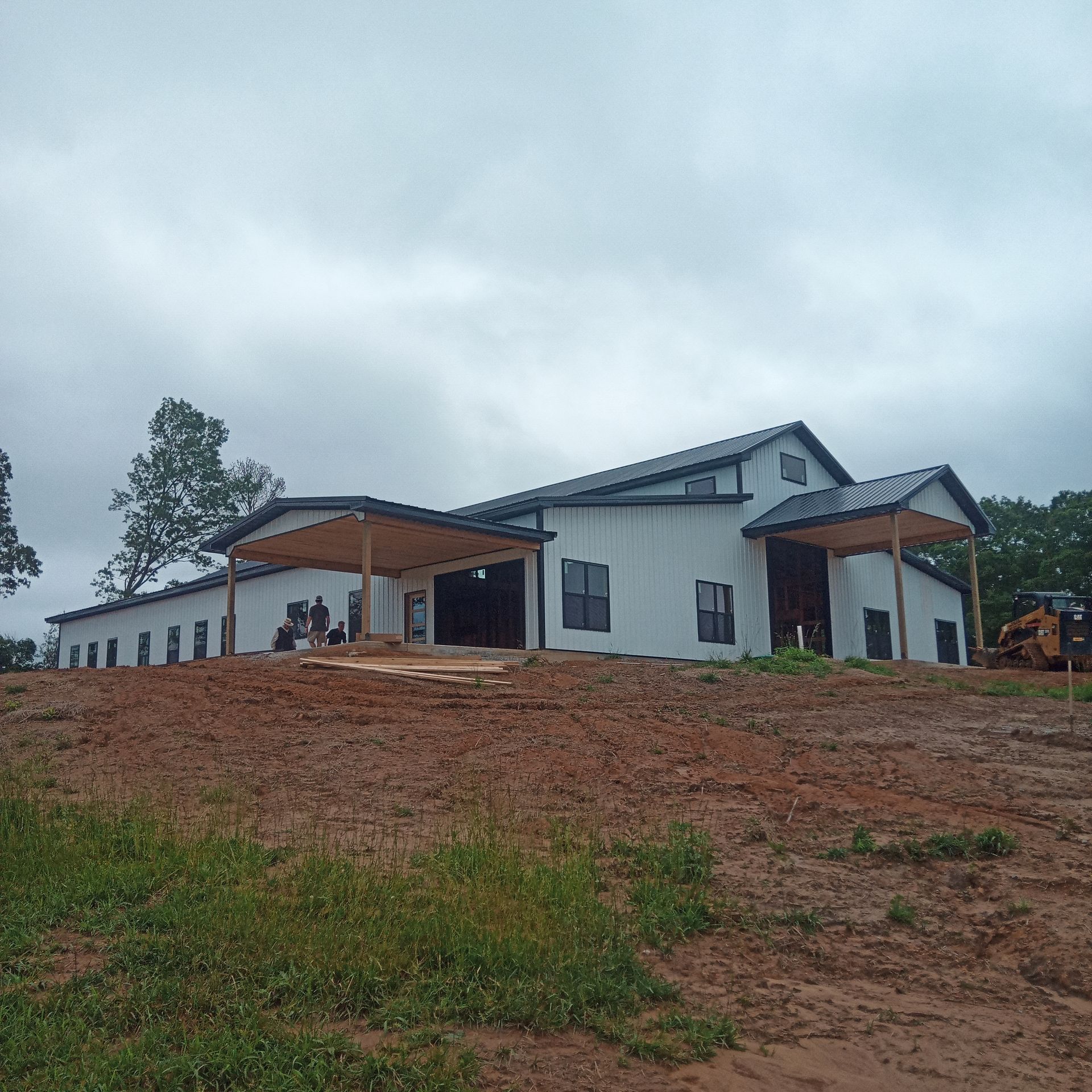 A large white house is sitting on top of a dirt hill.