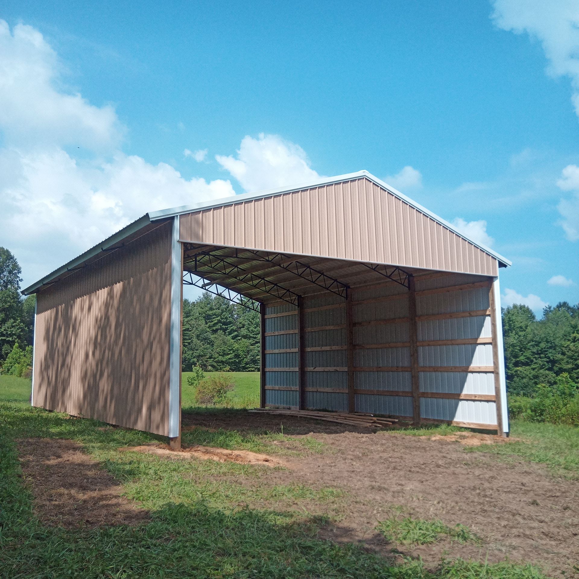 A shed in the middle of a field with trees in the background