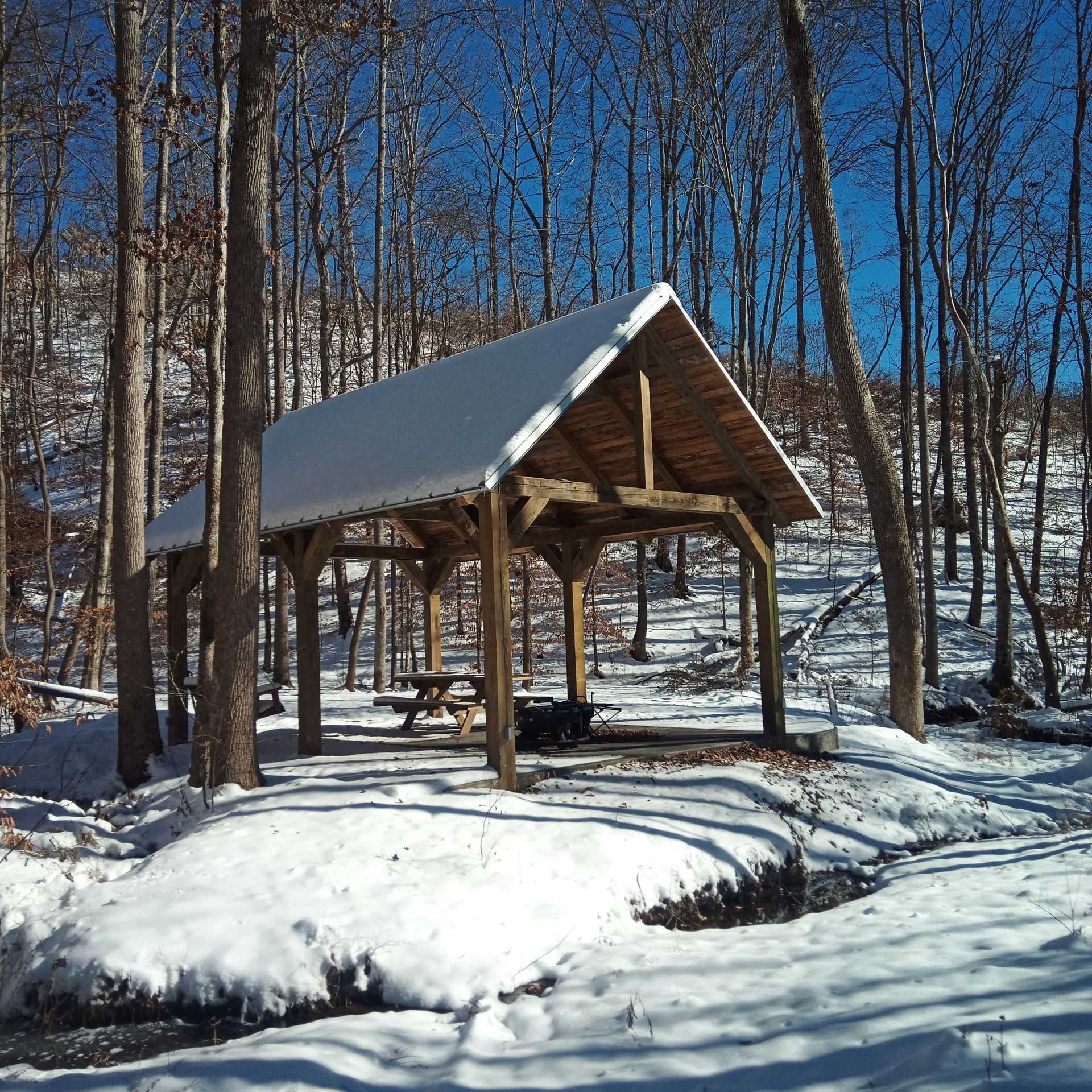 A snow covered shelter with a picnic table underneath it