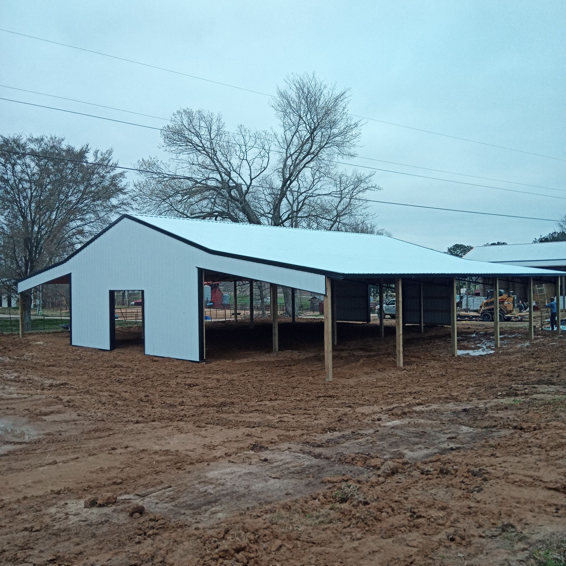 A white building with a black trim sits in the middle of a dirt field