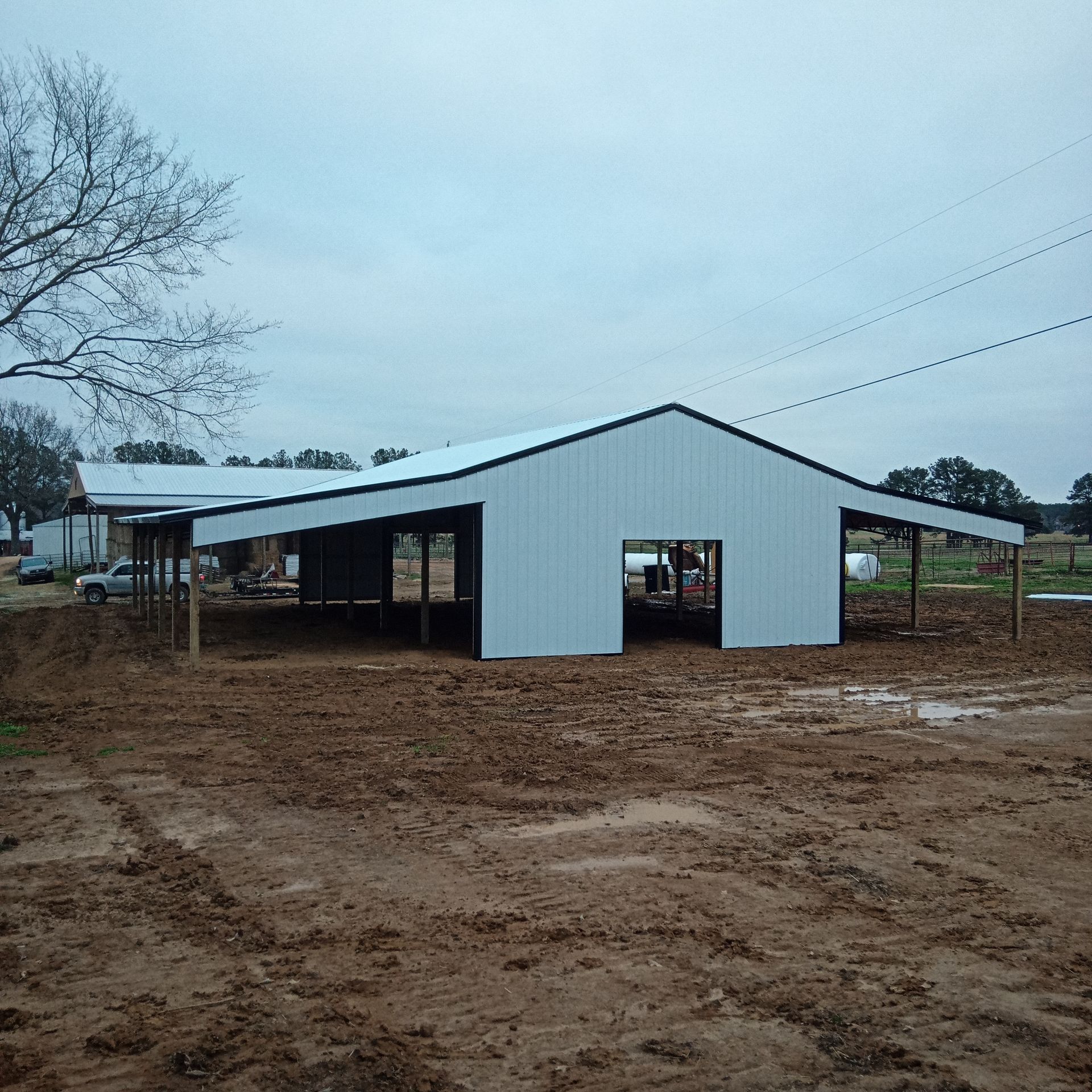 A white barn is sitting in the middle of a dirt field