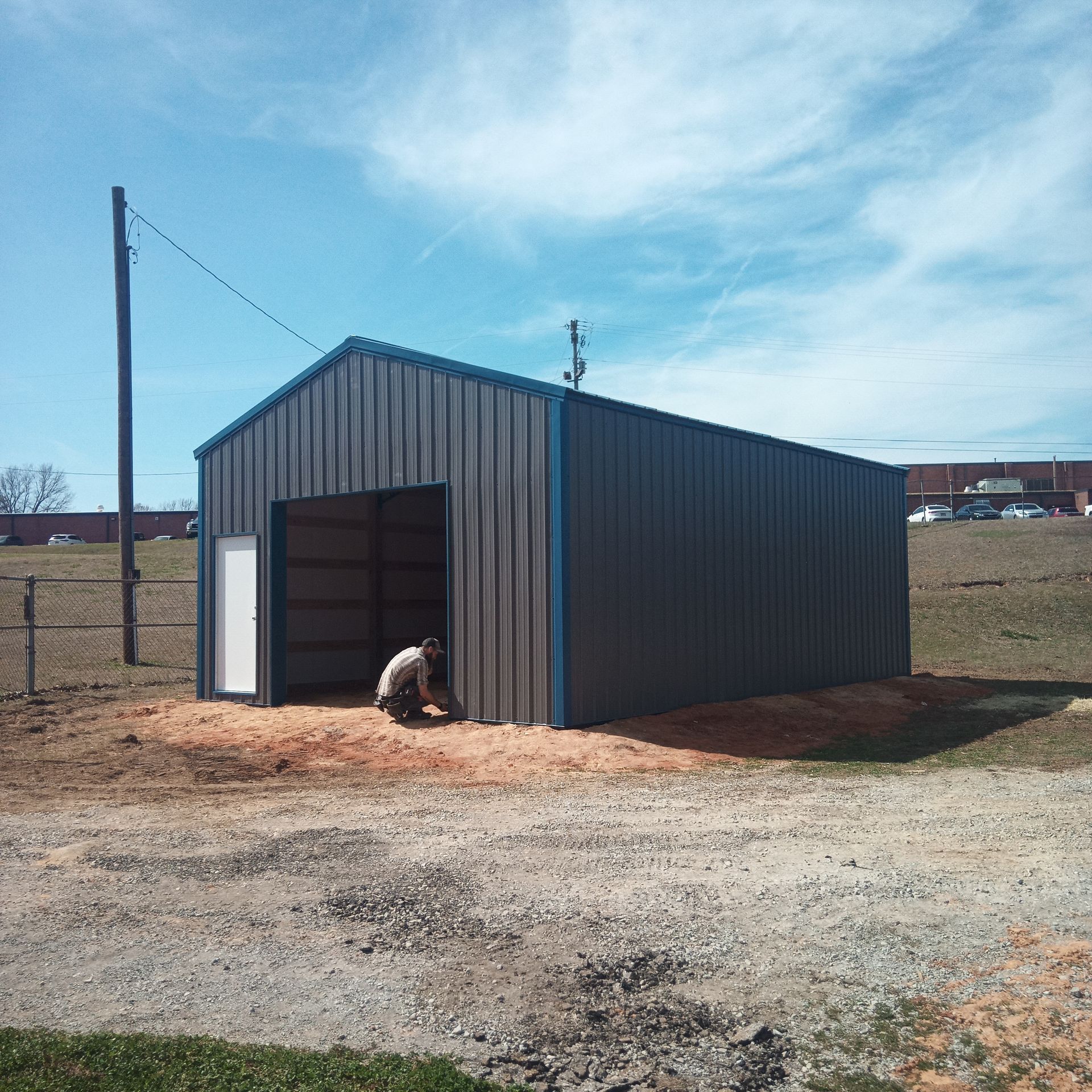 A man is kneeling in front of a metal building