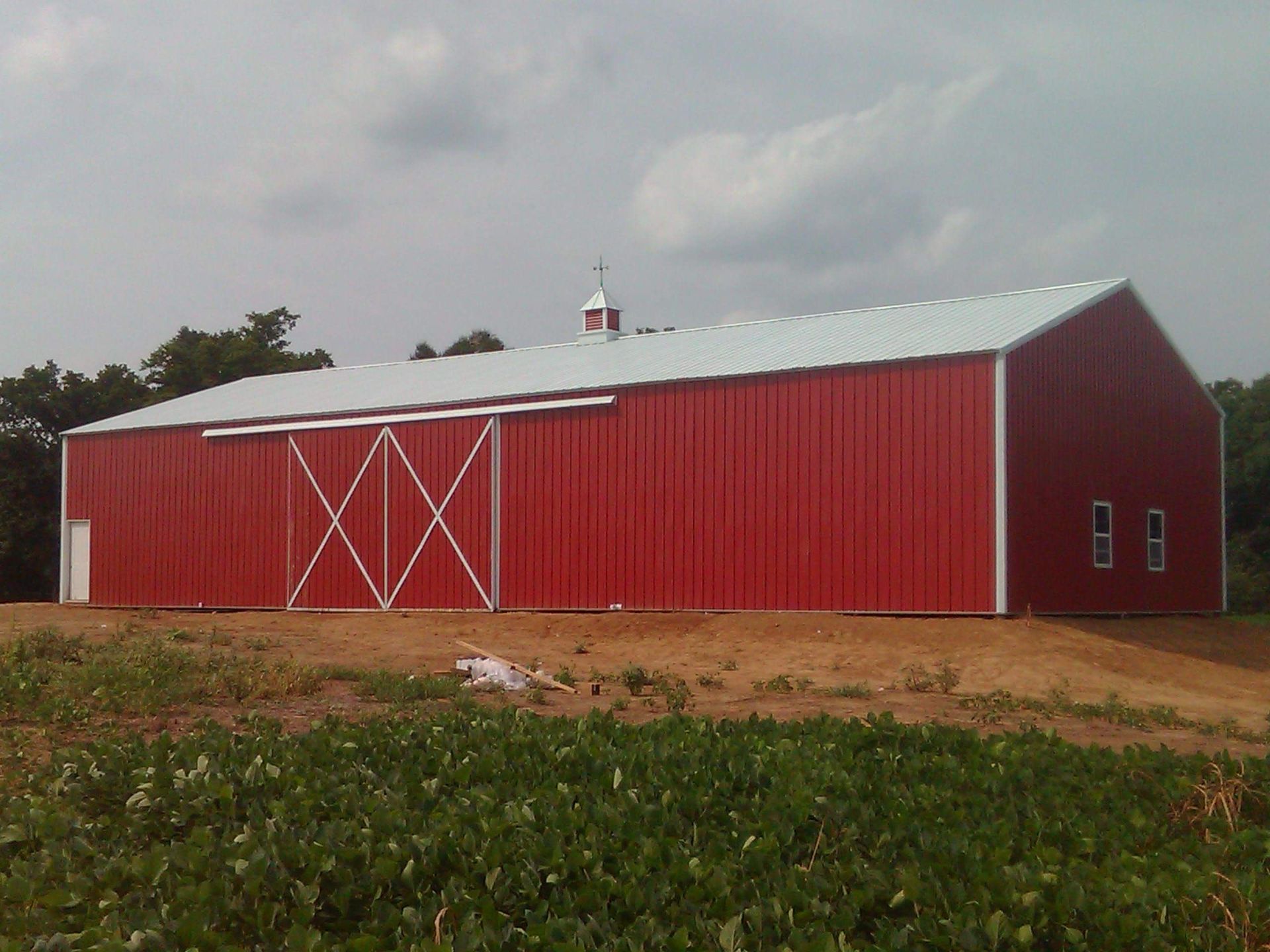 A large red barn with a white roof is sitting in the middle of a field.