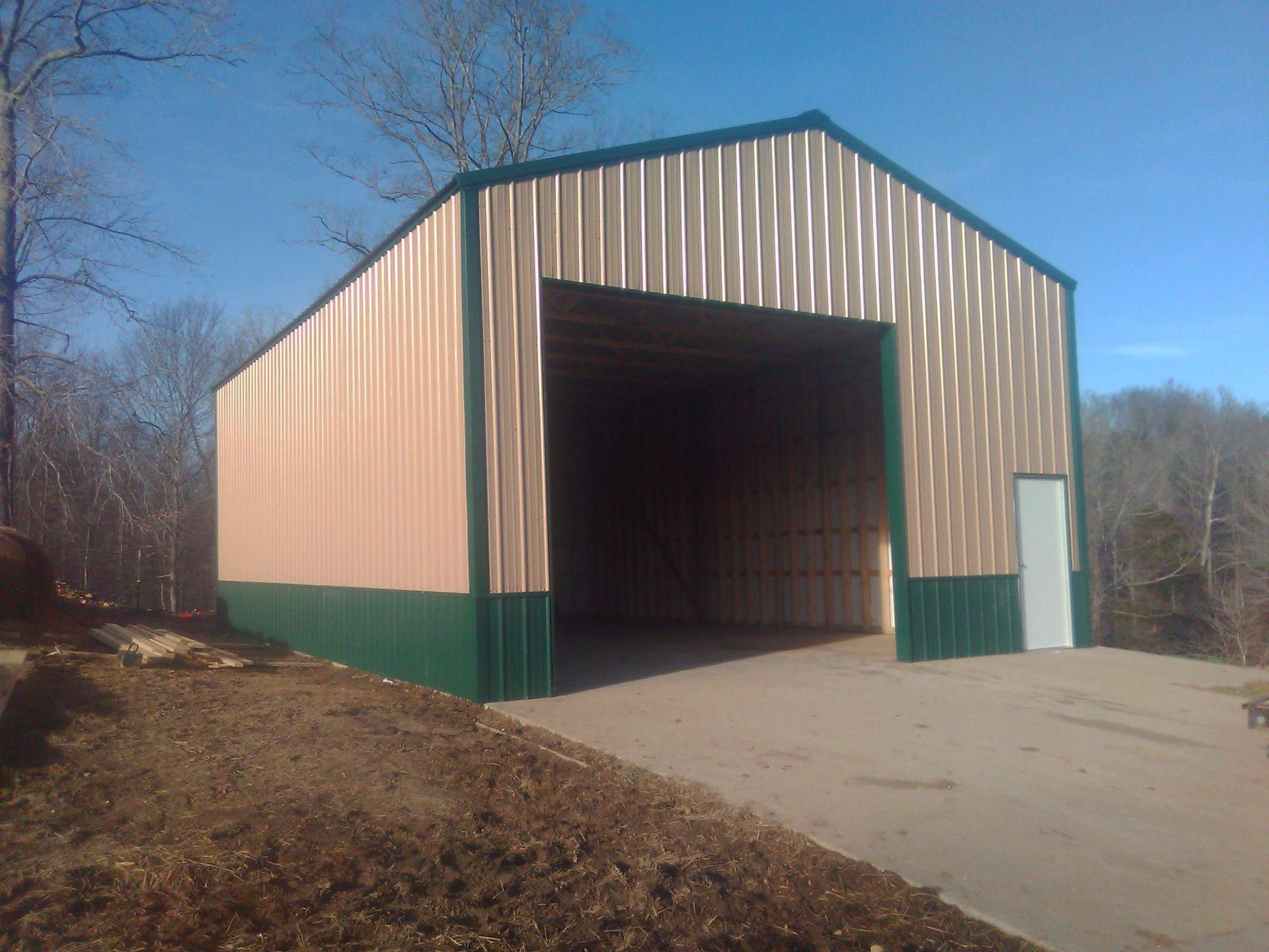 A large metal building with a green trim is sitting on top of a dirt hill.