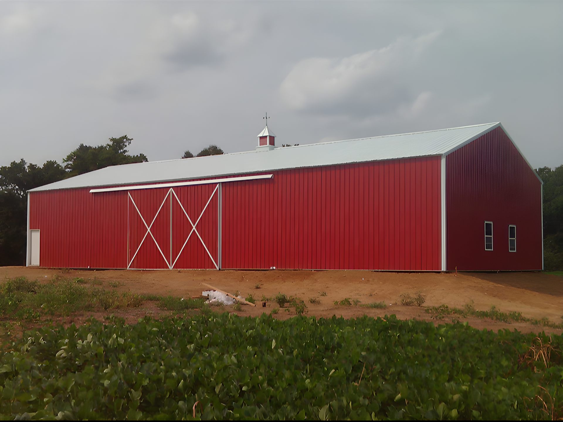 A large red barn with a white roof is in a field