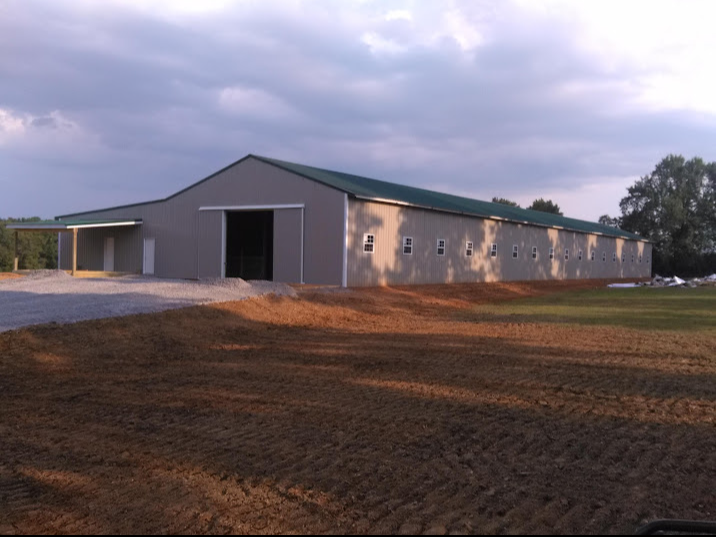 A large building with a green roof sits in the middle of a dirt field