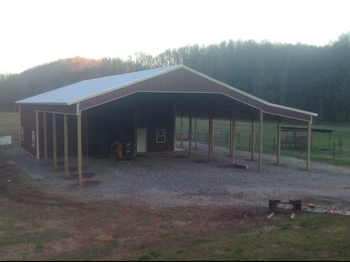 A large brown building with a white roof is in the middle of a field