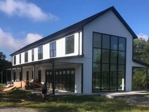 A large white house with a black roof and a lot of windows.