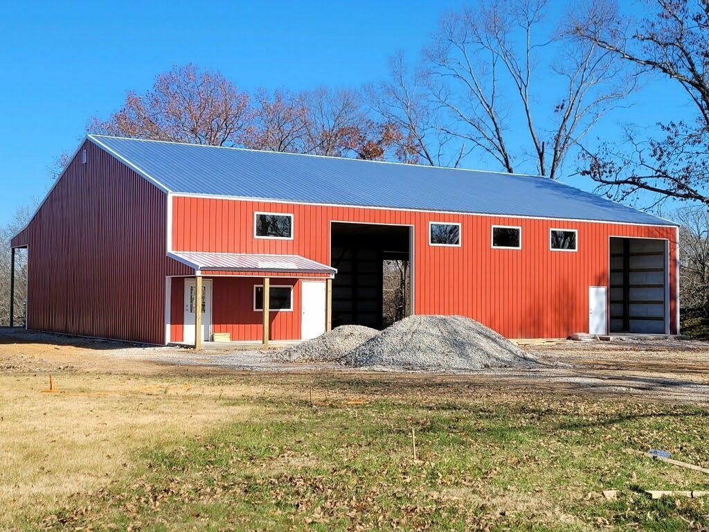 A large red barn is being built in a grassy field.