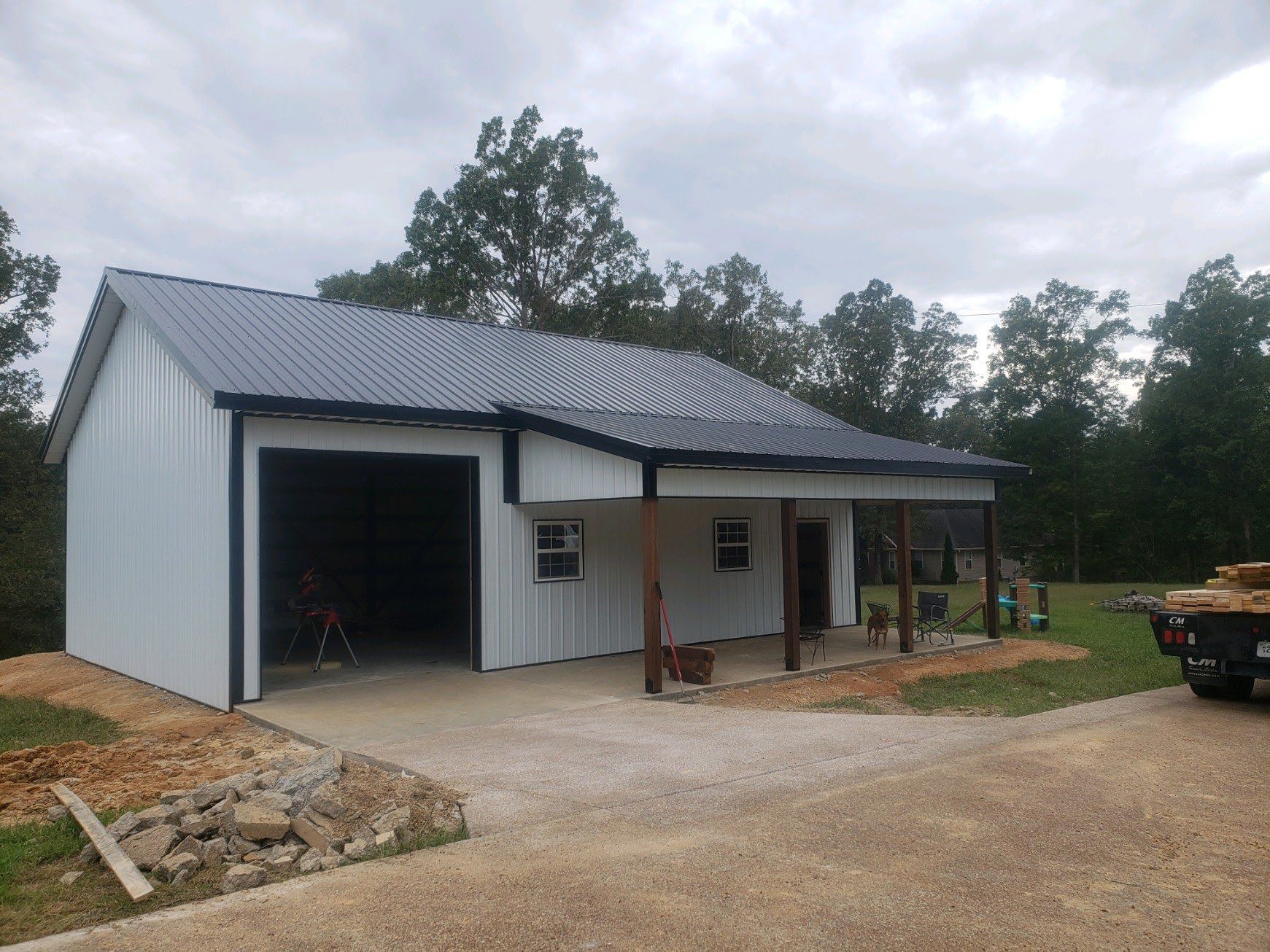 A white garage with a black roof and a porch.