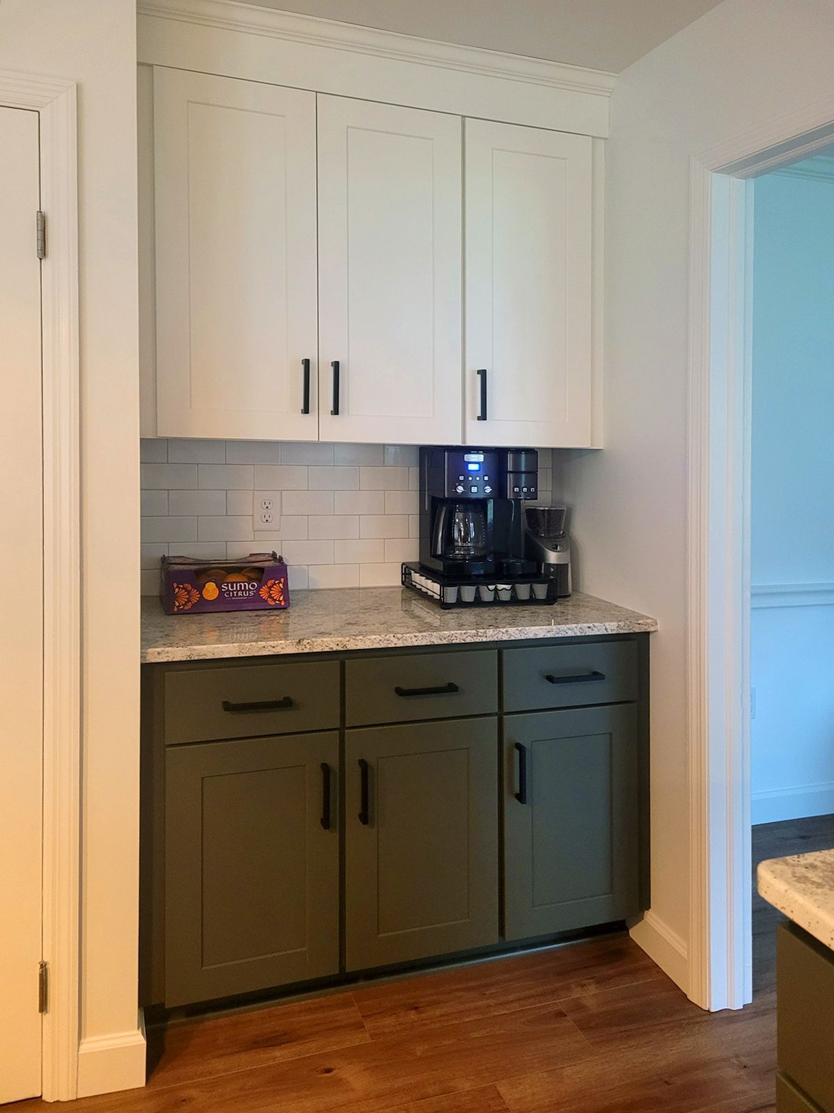 A kitchen with green cabinets and a coffee maker