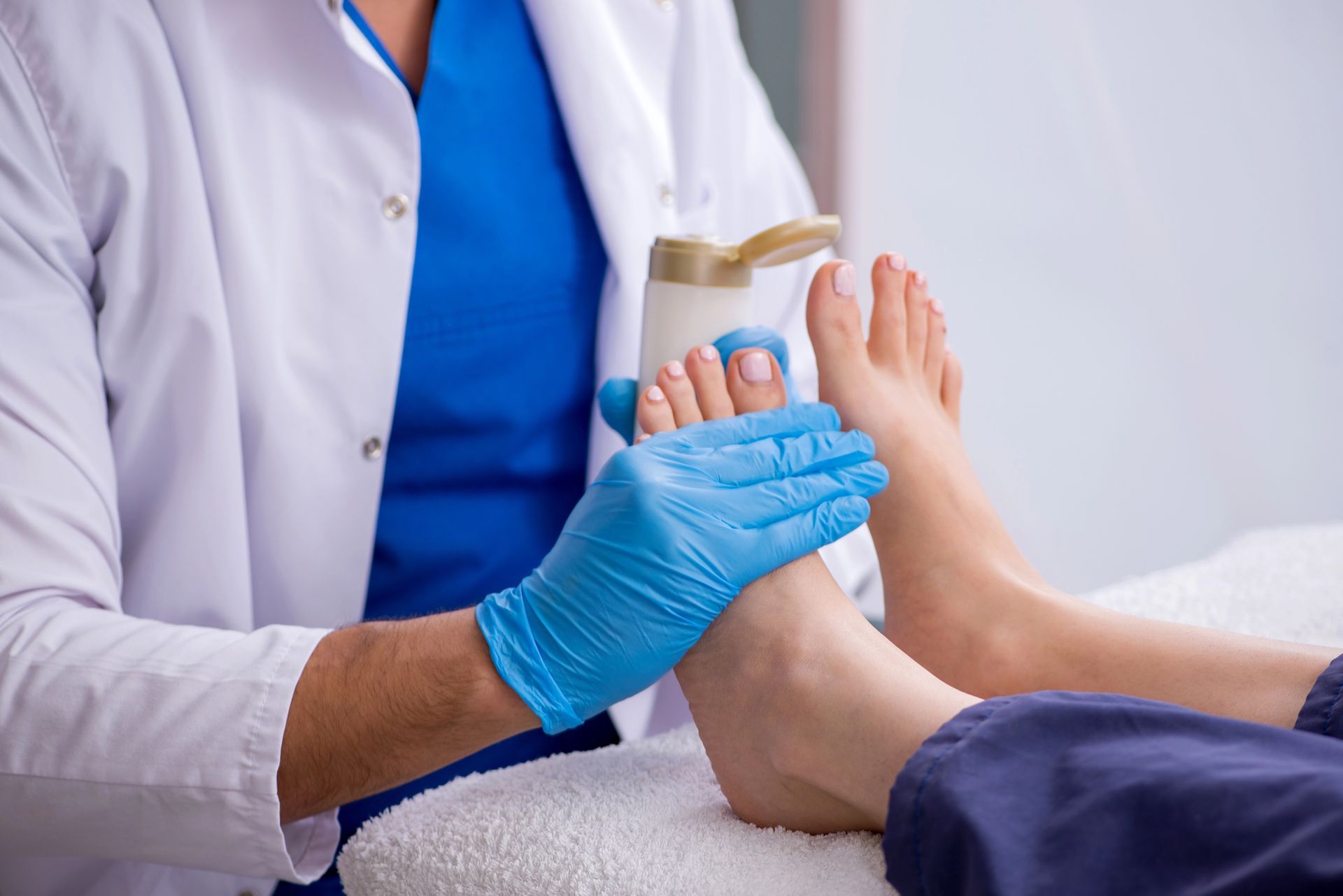 Médico examinando el pie de un paciente con guantes azules en una clínica.