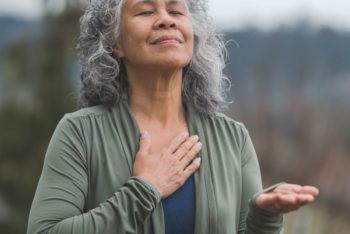 woman holding chest and breathing outside