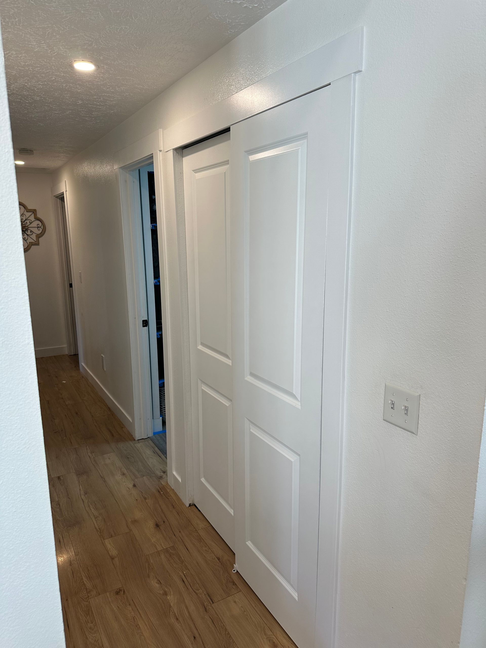 Hallway with white sliding closet doors, light wood floor, and recessed lighting.