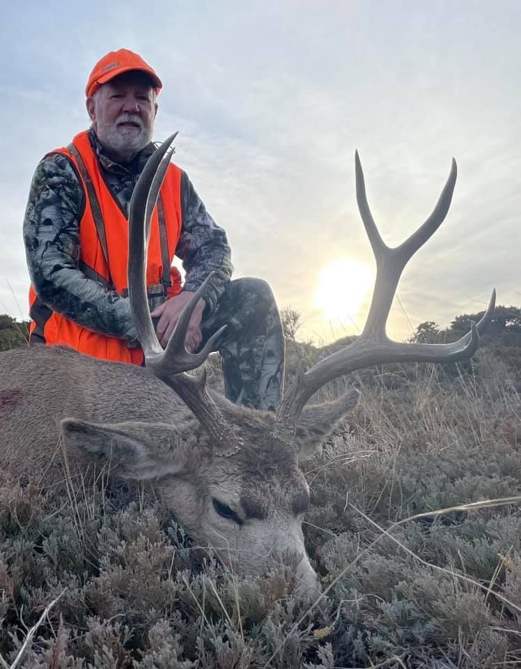 Man posing with deer in a forest